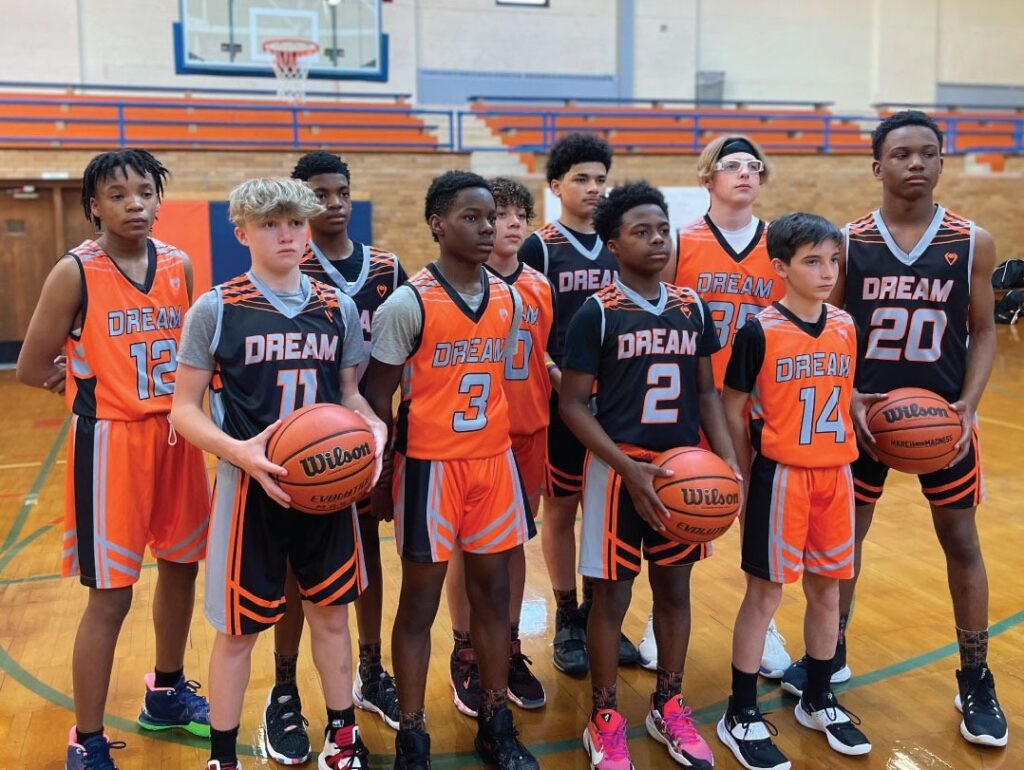 A youth boy's basketball team stands looking off camera, wearing Imperial Point custom sublimated uniforms with three players holding basketballs.