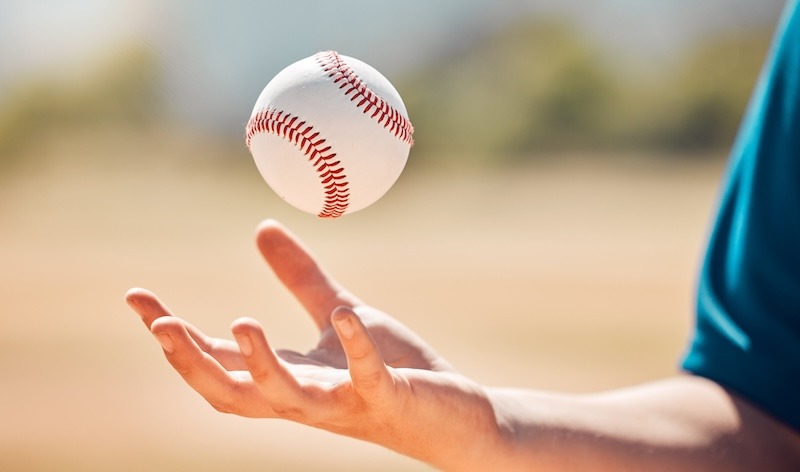 A close-up of a baseball suspended above a person's hand, emphasizing the moment before a catch.
