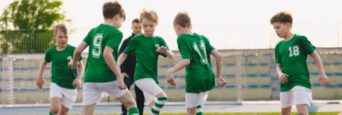 A group of children in green jerseys playing soccer.
